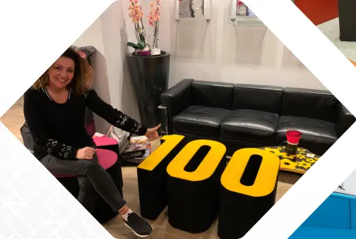LogoHocker Tisch in Form einer 100 steht vor einem Sofa